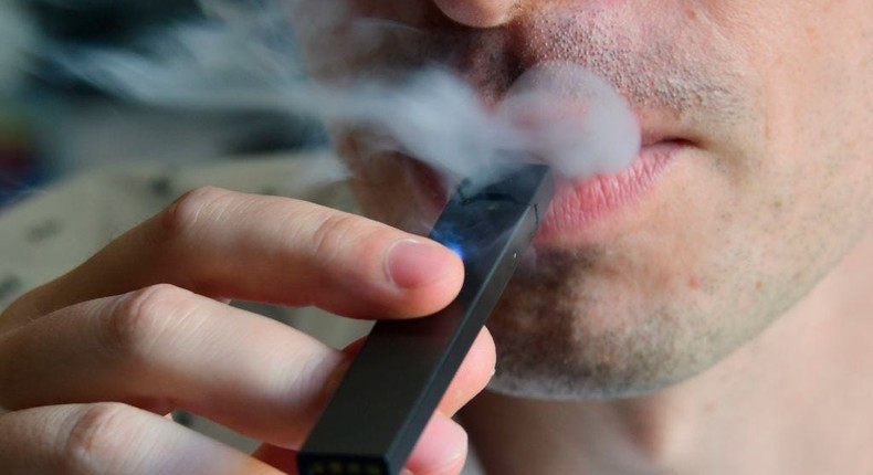 An illustration shows a man exhaling smoke from an electronic cigarette in Washington, DC on October 2, 2018.