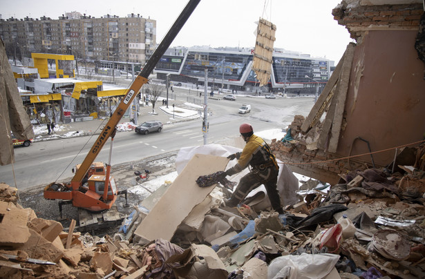 Ukraiński ratownik usuwa gruz z budynku po ostrzale w Charkowie na Ukrainie