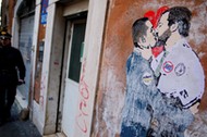 An Italian Carabiniere stands next to a mural depicting Northern League's leader Matteo Salvini and 