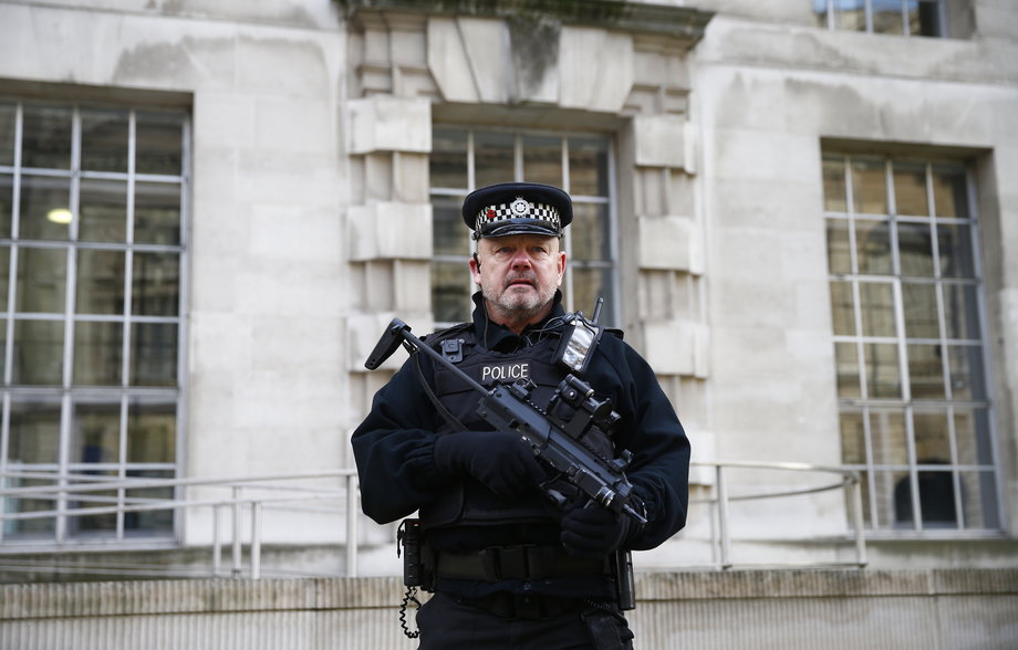 An armed police officer stands on duty outside a government building in Westminster, central London.