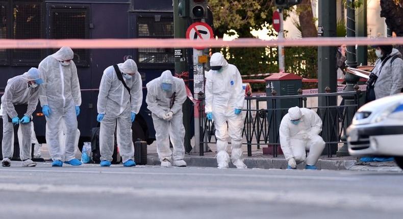 Police officers conduct a search at the front of the French embassy after two motorcyclists threw a hand grenade injuring the guard in central Athens on November 10, 2016