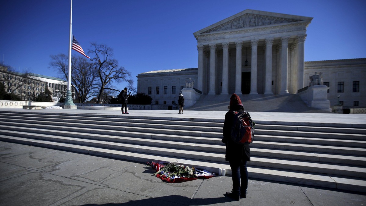 Flowers are seen as a woman stands in front of the Supreme Court building in Washington D.C. after t