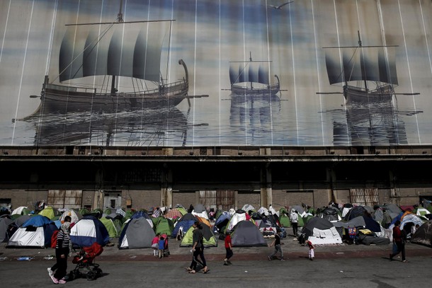 Refugees and migrants walk at a makeshift camp at the port of Piraeus, near Athens