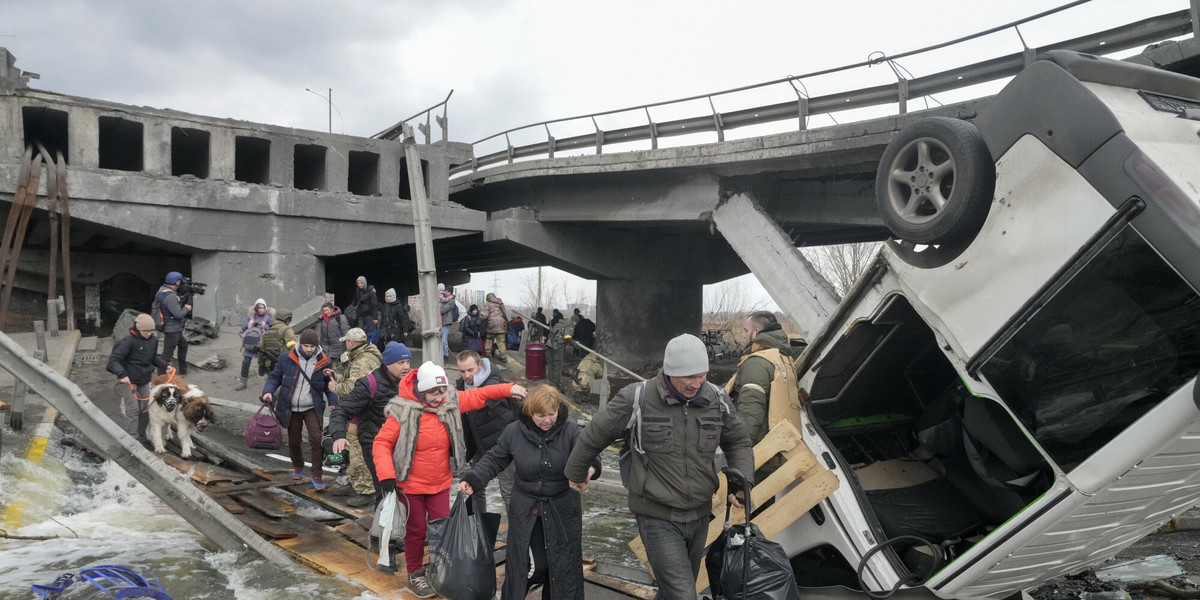 Ludzie przechodzą pod zniszczonym mostem podczas ucieczki z miasta Irpin niedaleko Kijowa w Ukrainie, poniedziałek 7 marca 2022 r.