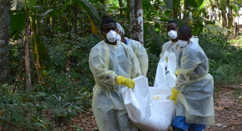 Red Cross volunteers, wearing protective clothing, carry the body of a person who died from Ebola during a burial in Monrovia, Liberia, on January 5, 2015