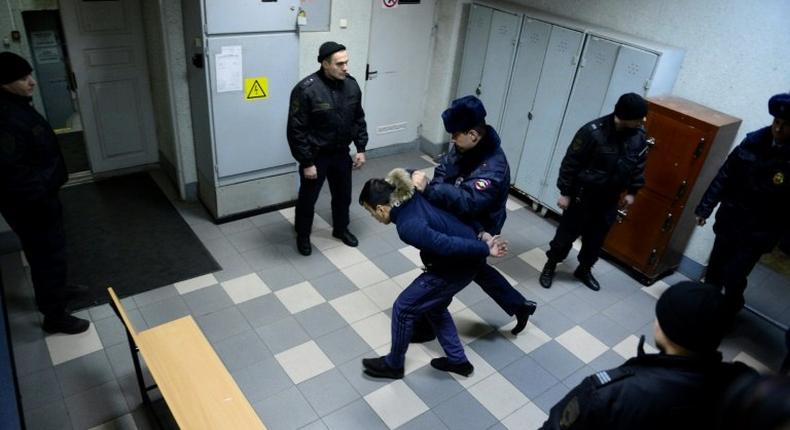 A police officer escorts a man suspected of involvement in the Saint Petersburg metro bombing inside a court building in Saint Petersburg on April 7, 2017