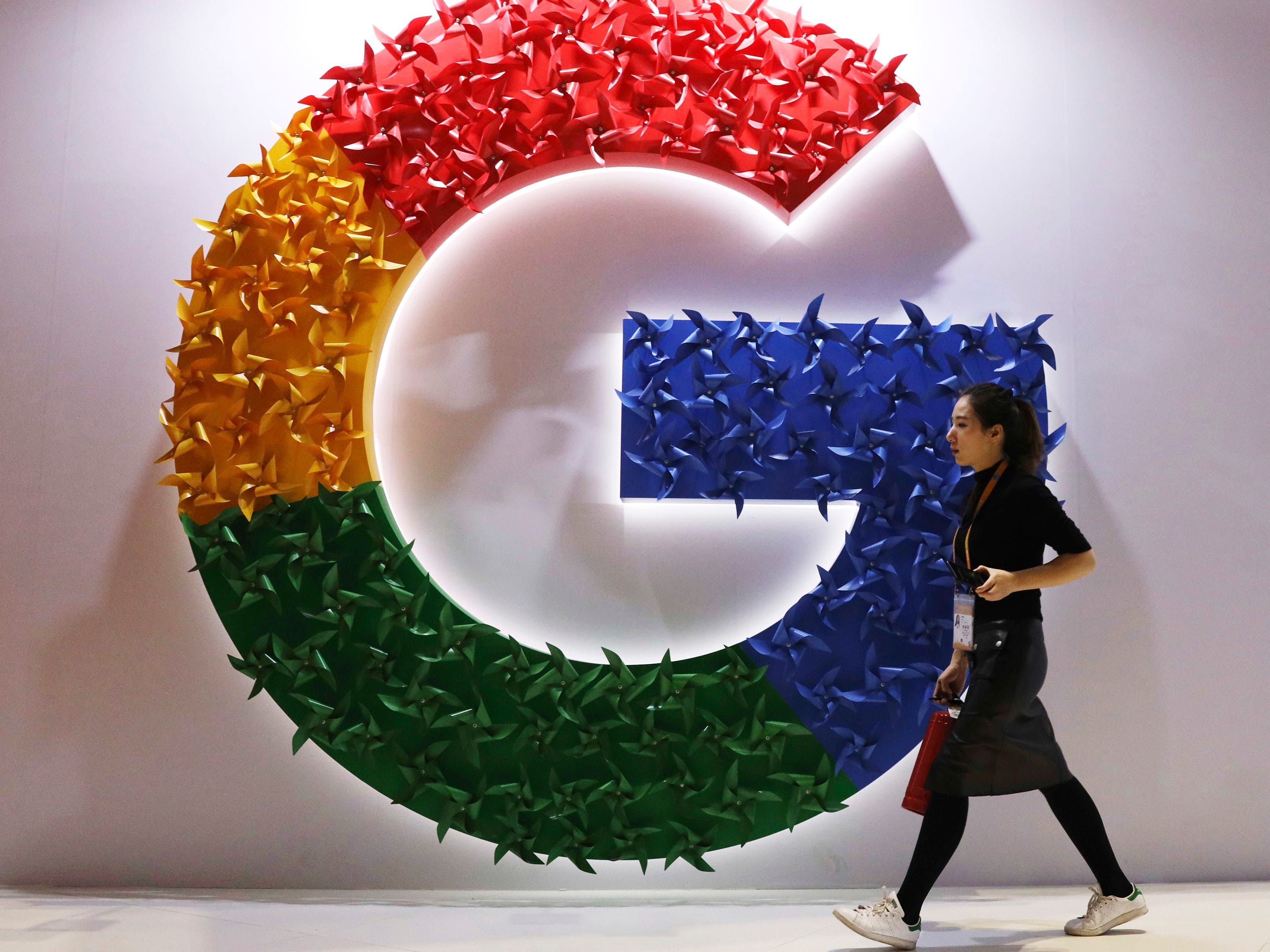 An employee walks past the Google logo.
