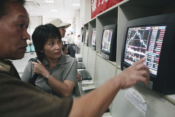 Inwestorzy sprawdzają notowania akcji w domu maklerskim w Szanghaju. Fot. Bloomberg