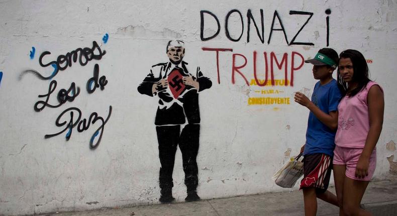 A mural of President Donald Trump, showing him wearing a Nazi swastika, in Caracas, next to the Spanish message: We are those of peace, November 14, 2017.