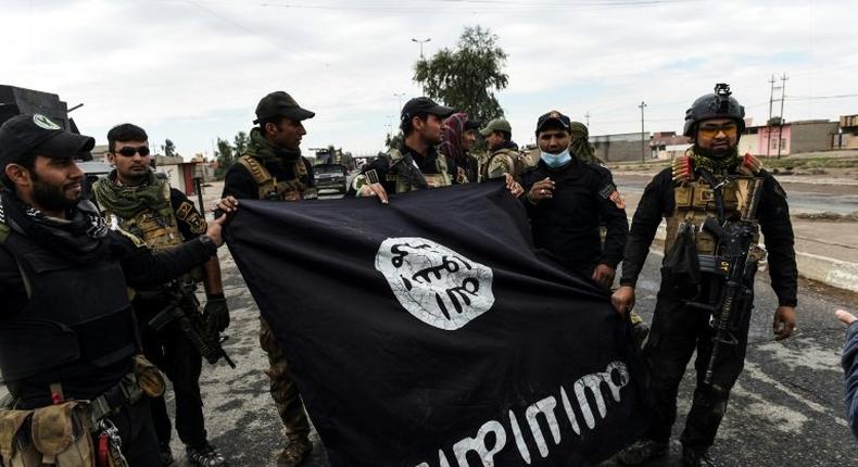 Iraqi soldiers pose with an Islamic State flag near Mosul on November 2, 2016