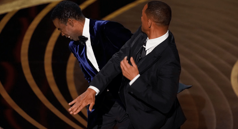 Will Smith, right, hits presenter Chris Rock on stage while presenting the award for best documentary feature at the Oscars on Sunday, March 27, 2022, at the Dolby Theatre in Los Angeles.(Chris Pizzello / Chris Pizzello/Invision/AP)