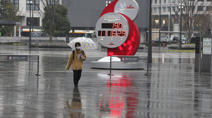 A tokiói nyári olimpiáig még hátralévő időt számláló óra előtt megy egy nő a japán fővárosban 2021. február 15-én. A koronavírus-járvány miatt 2020-ról 2021-re halasztott ötkarikás játékokat a tervek szerint 2021. július 23. és augusztus 8. között rendezik meg, de a legfrissebb közvéleménykutatások szerint a lakosság 80 százaléka vagy tovább halasztaná vagy meg sem rendezné az olimpiát. / Fotó: MTI/AP/Szaszahara Kodzsi