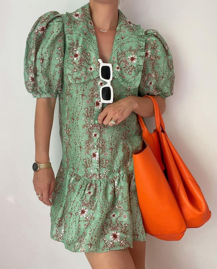 L’influenceuse Naaomi Ross porte une petite robe verte et un sac rouge assortis à des lunettes de soleil blanches très tendance.