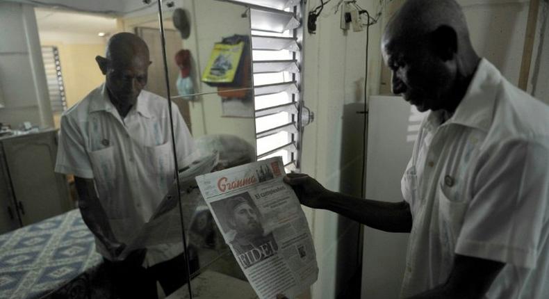 Luis Monteagudo Arteaga, a Cuban former guerrilla fighter, who joined Argentinean guerrilla leader Che Guevara in Congo, holds a newspaper with the frontpage dedicated to late Cuban revolutionary leader Fidel Castro at his home November 30, 2016