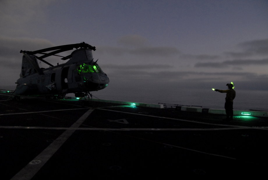 Aviation Boatswain’s Mate Airman Zach Byrd directs a CH-46E Sea Knight helicopter assigned to the Purple Foxes of Marine Medium Helicopter Squadron 364 during nighttime flight operations aboard the amphibious transport dock ship USS Green Bay.