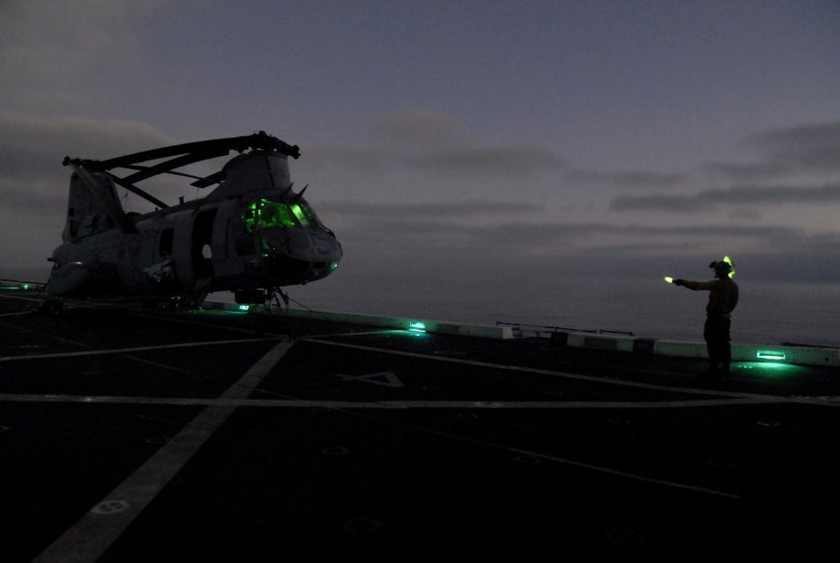 Aviation Boatswain’s Mate Airman Zach Byrd directs a CH-46E Sea Knight helicopter assigned to the Purple Foxes of Marine Medium Helicopter Squadron 364 during nighttime flight operations aboard the amphibious transport dock ship USS Green Bay.