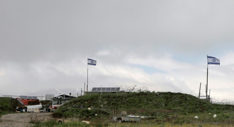 Israeli flags fly over a military base near the border fence with Syria in the Israeli-annexed Golan Heights, south of the Druze village of Majdal Shams