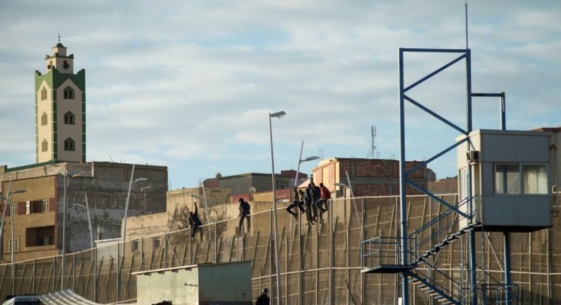 African immigrants sit on a border fence separating Morocco from the Spanish enclave of Melilla in 2014