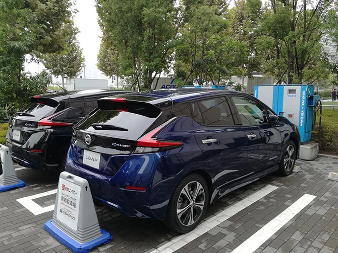 Nissany Leaf przed iMARK PLACE w Yokohamie. W tle stacja ładowania 3 x V2B