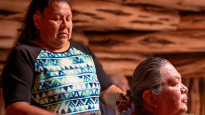 Navajo woman helping her husband braid his hairgrandriver/Getty Images