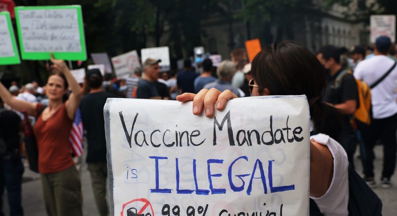 People hold up a protest signs as people gather at City Hall to protest vaccine mandates on August 09, 2021 in New York City.
