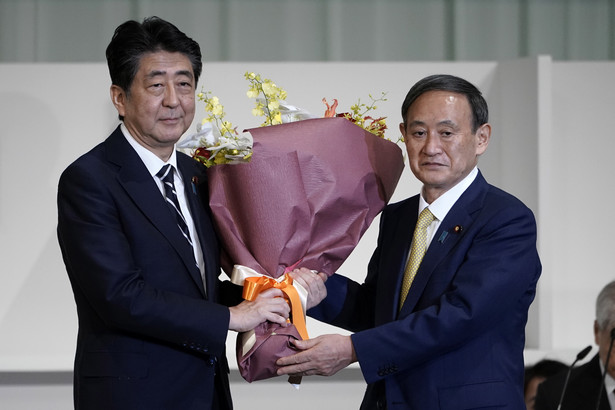 epa08667594 Japan's Prime Minister Shinzo Abe (L) presents Chief Cabinet Secretary Yoshihide Suga (R) flowers after Suga was elected as new head of Japan's ruling party during the Liberal Democratic Party's (LDP) leadership election in Tokyo, Japan, 14 September 2020. EPA/EUGENE HOSHIKO / POOL Dostawca: PAP/EPA.