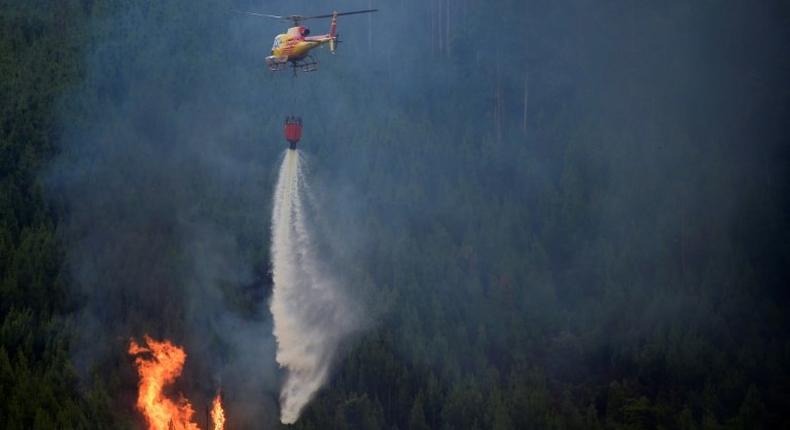 A helicopter drops water over a wildfire in Carvalho, next to Pampilhosa da Serra. The huge forest fire that erupted in central Portugal Saturday has killed at least 64 people and injured more than 100