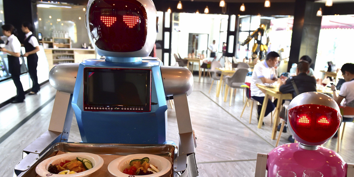 Robot couple Xiaolan (L) and Xiaotao carry trays of food at a restaurant in Jinhua, Zhejiang province, China, May 18, 2015.