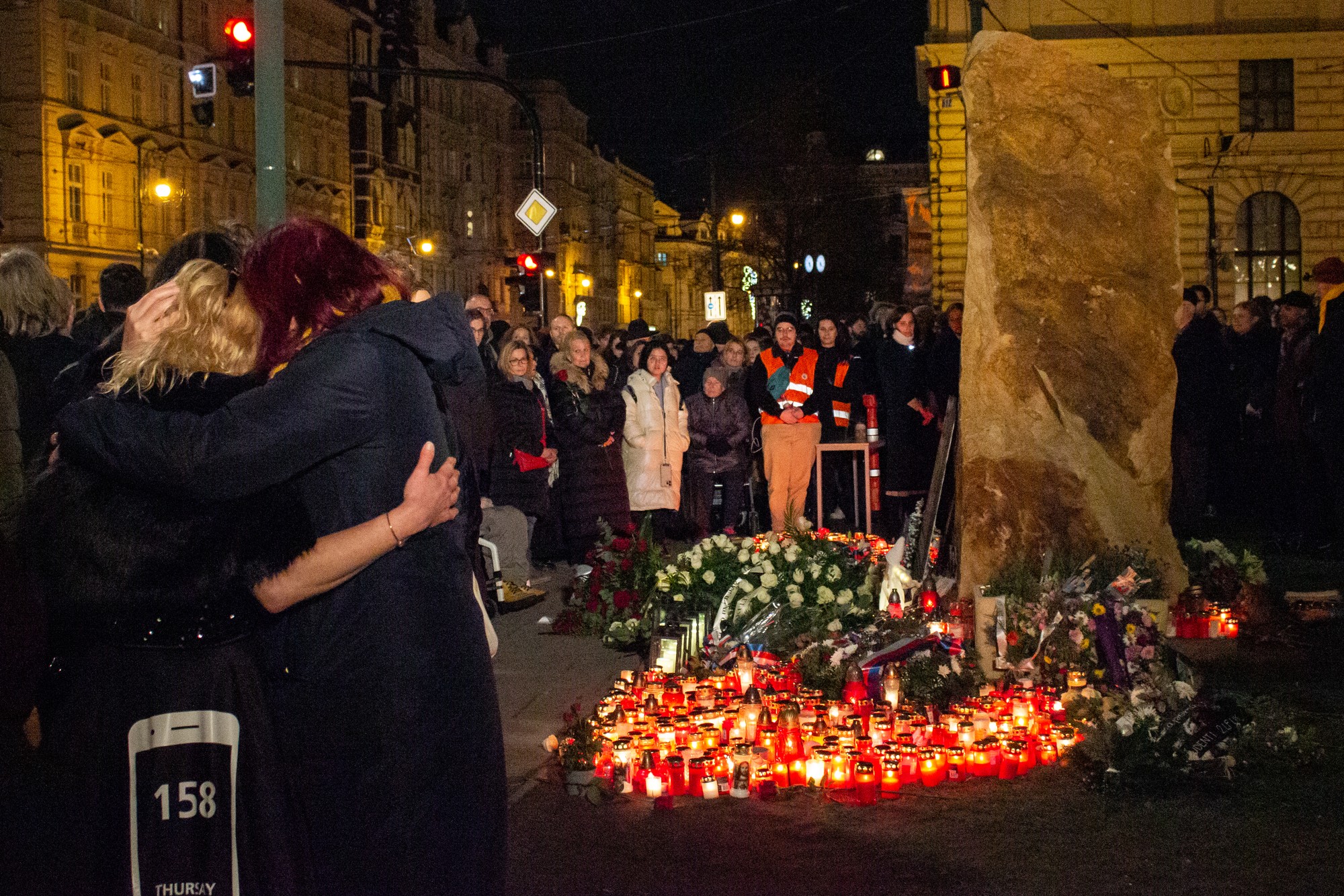 Na snímke ľudia zhromaždení pred pamätníkom obetí streľby z 21. decembra 2023 pred budovou Filozofickej fakulty Univerzity Karlovej počas pietnej spomienky v deň prvého výročia.