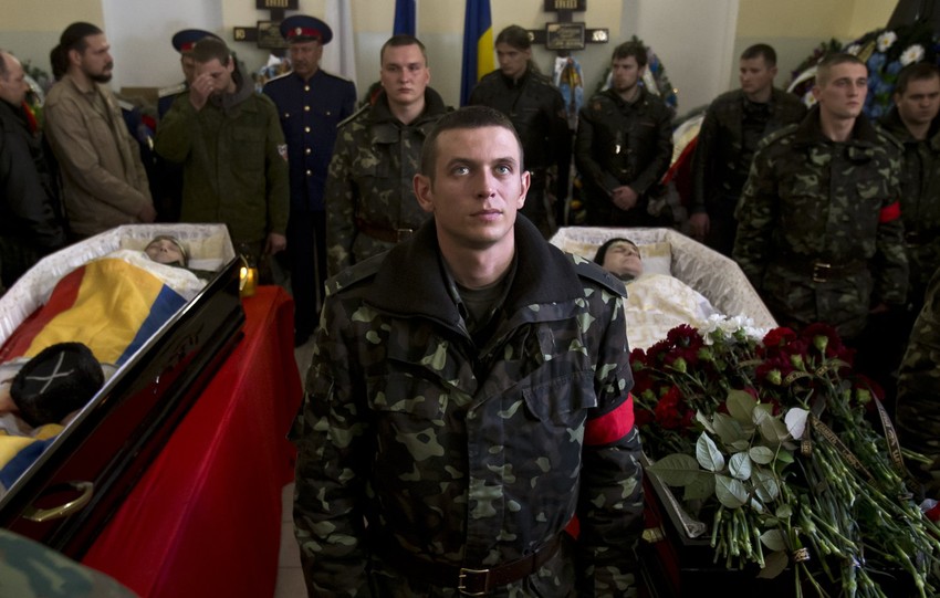 Ukrajinski vojnik između kovčega dvojice poginulih