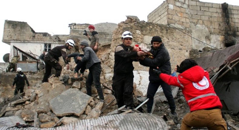 Syrian Civil Defence volunteers rescue children from a damaged building following a reported airstrike that targeted the Idlib bus station on January 18, 2017