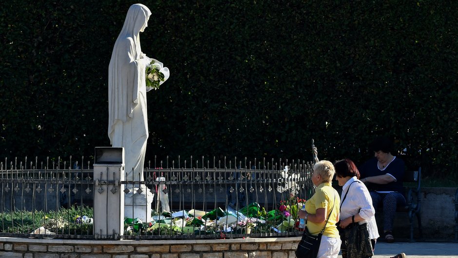 Piegrzymi klęczący przed pomnikiem Maryji przy kościele św. Jakuba