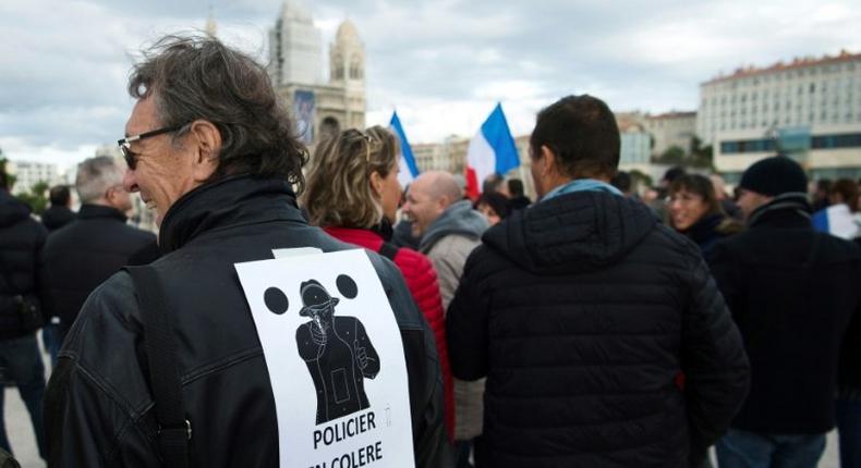 A man wears a poster on his back which translates as angry policemen during a demonstration over mounting attacks on officers and to call for reinforcements and more resources, on December 3, 2016 in Marseille, France