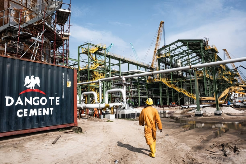 A Dangote Cement Plc logo stands on a barrier at the under-construction Dangote Industries Ltd. [Tom Saater/Bloomberg via Getty Images]