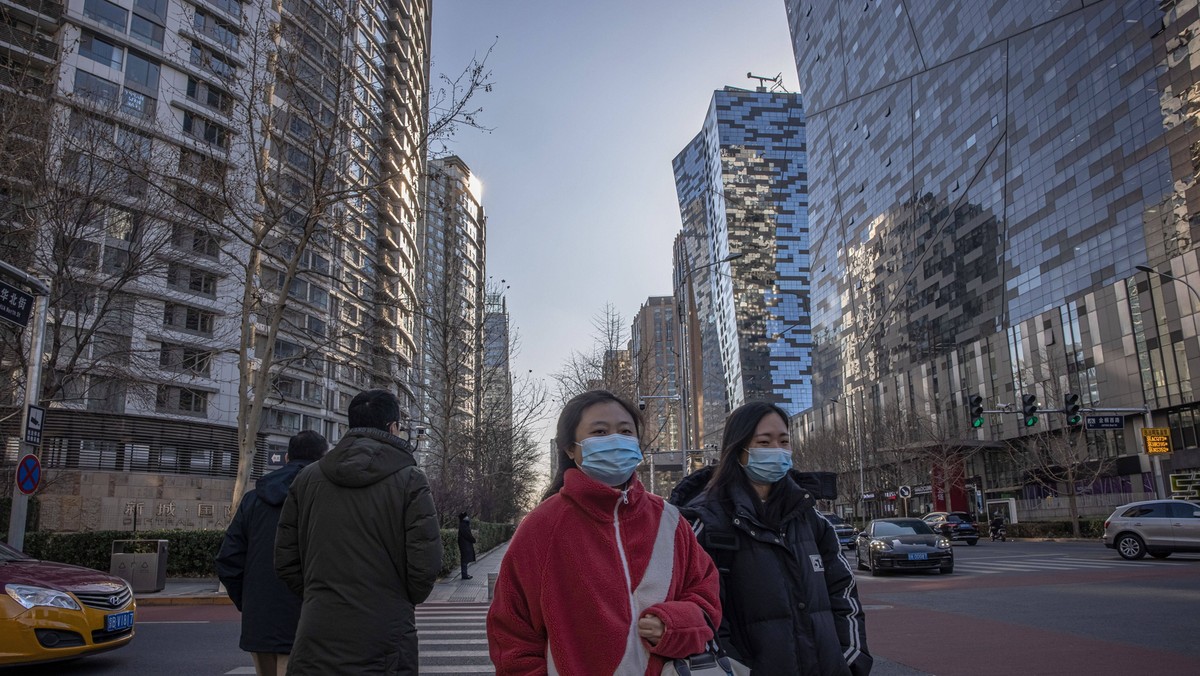 epa09639837 People wearing protective face masks cross a road in the business district of Beijing, China, 13 December 2021. China's National Health Commission reported over 100 new Covid-19 cases, including 80 locally transmitted cases in the Chinese mainland, on 12 December. EPA/ROMAN PILIPEY Dostawca: PAP/EPA.