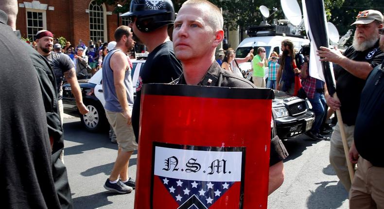 A white supremacist holds a shield with National Socialist Movement symbols on it as he arrives at a rally in Charlottesville, Virginia, U.S., August 12, 2017.