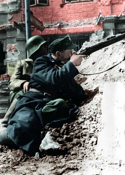 Powstanie Warszawskie: powstańcy z batalionu „Kiliński” ostrzeliwują budynek PAST-y z poziomu ul. Zielnej (20 sierpnia 1944, domena publiczna).