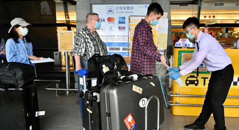 A worker sprays sprays hand sanitizer onto passengers arriving in March 2020 at Taoyuan Airport in Taiwan, one of the few places for which the United States has completely lifted its warning to avoid travel due to the coronavirus