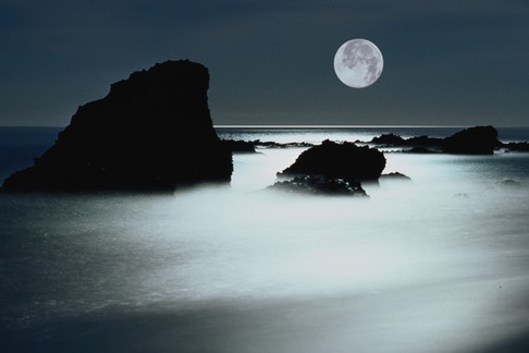 Full moon over rocky shoreline