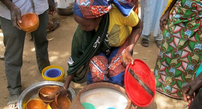 A photo taken on February 23, 2017 shows a woman selling bil-bil, a homemade brew made from millet, sorghum or corn, in Mazogo, in the extreme north of Cameroon