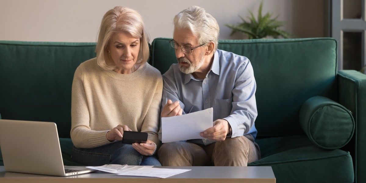 Serious mature couple calculating bills, checking domestic finances