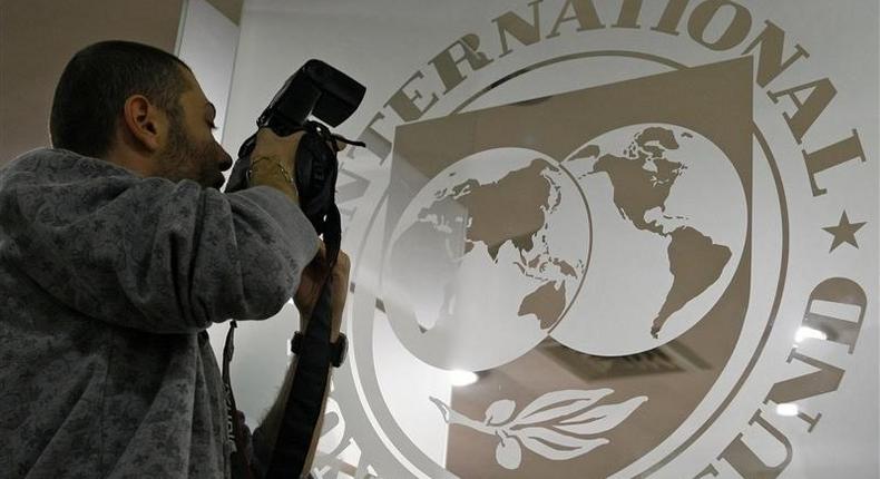 A photographer takes pictures through a glass carrying the International Monetary Fund (IMF) logo during a news conference in Bucharest, file. 