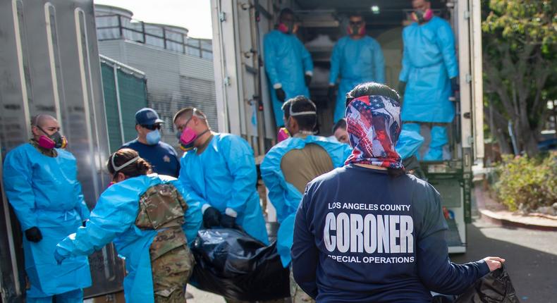 In this Jan. 12, 2020 file photo, provided by the LA County Dept. of Medical Examiner-Coroner Elizabeth Liz Napoles, right, works alongside with National Guardsmen who are helping to process the COVID-19 deaths to be placed into temporary storage at LA County Medical Examiner-Coroner Office in Los Angeles.