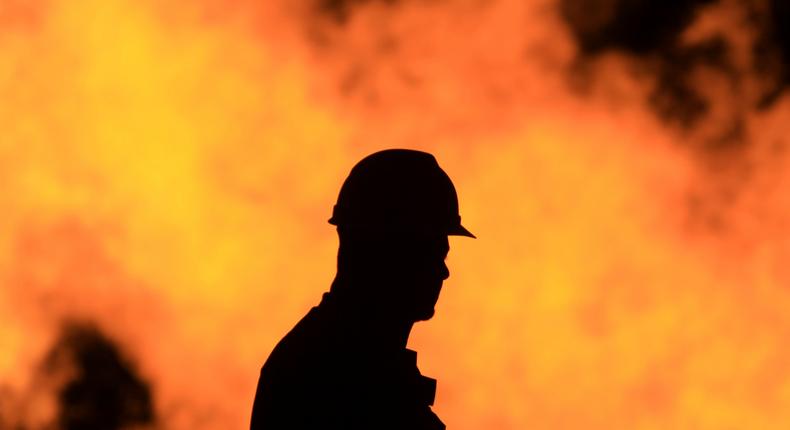 An unidentified oil worker walks in front of a natural gas flame burning off in the Persian Gulf desert oil field of Sakhir, Bahrain.