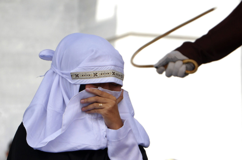 Funkcjonariuszka policji szariatu wymierza chłostę kobiecie w Aceh w Indonezji. Aceh jest jedynym regionem Indonezji, gdzie obowiązuje prawo szariatu.