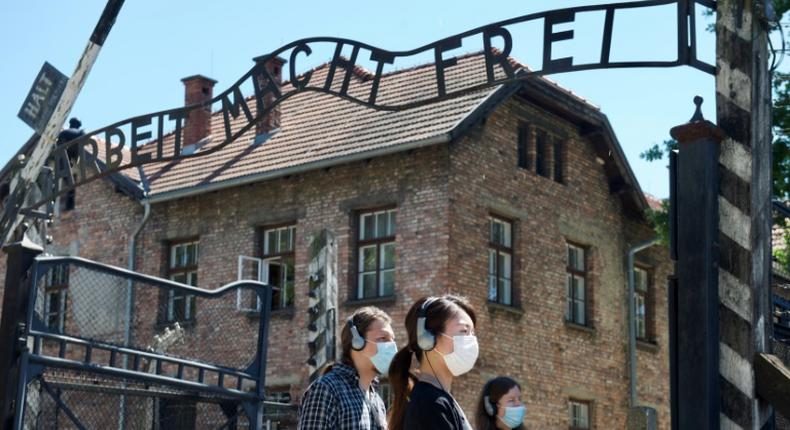 As the site reopens following Coronavirus lockdown, visitors to Auschwitz contemplate the  entrance gate with its inscription Work sets you free