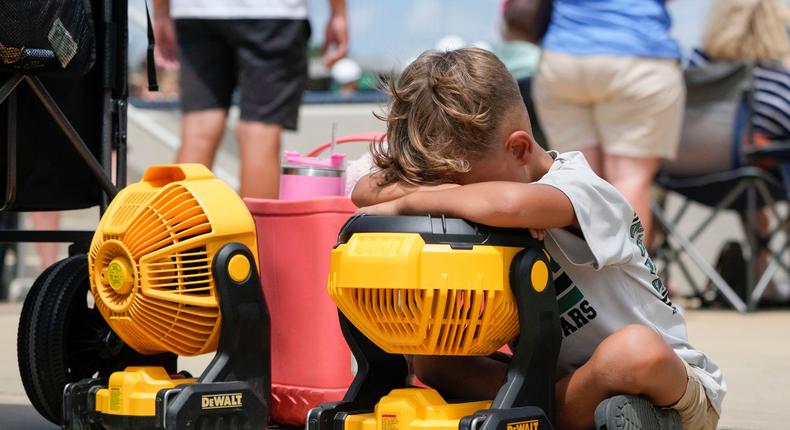 A kid holds his face to a portable fan to cool off during a Little League tournament in Ruston, La., as the area experiences a record-setting heat wave.Associated Press