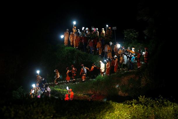 Rescue members walk during the burial of a companion who died after flooding and mudslides caused by