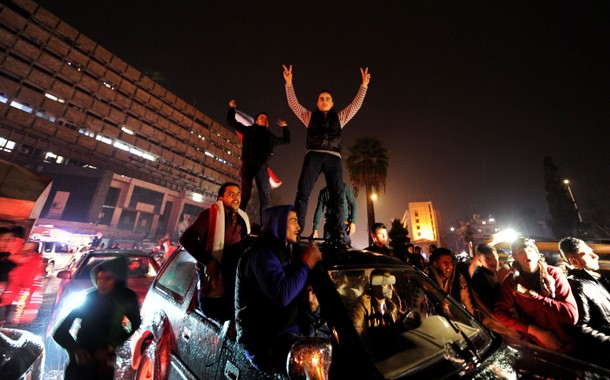 Supporters of Syria's President Bashar al-Assad carry their national flags and gesture as they tour 