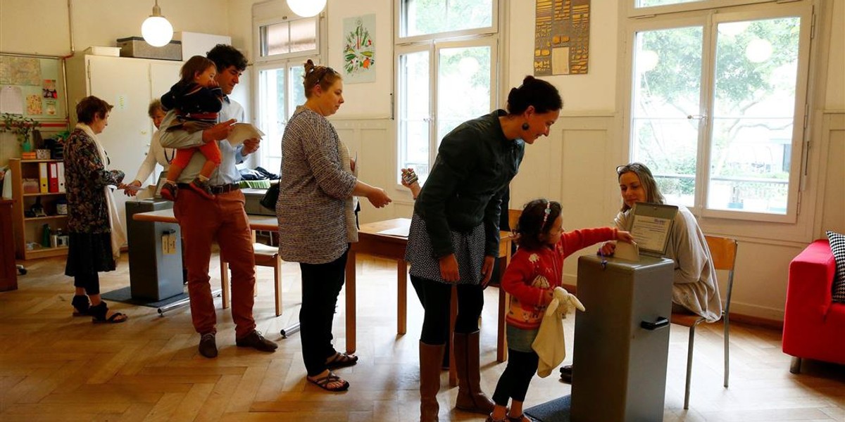 People cast their ballots during a vote on whether to give every adult citizen a basic guaranteed monthly income of 2,500 Swiss francs ($2,560), in a school in Bern